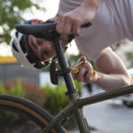 Peter heeft een helm op en werkt aan zijn fiets in Roermond om zadelpijn te voorkomen