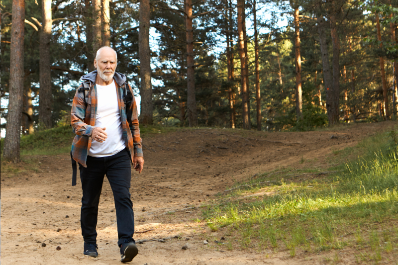 Johan heeft artrose en loopt door het bos in een wit shirt met een geruite blouse.