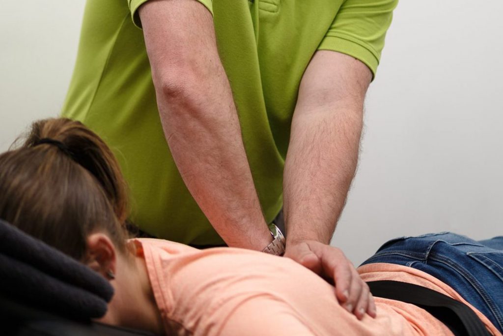 Vrouw ligt plat op haar buik en ontvangt manuele therapie van een fysiotherapeut bij FYSIO plus voor haar rugklachten